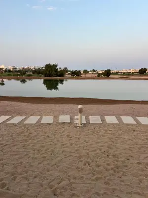 a pole in the sand next to a body of water at Cyan Lakefront 3BR Townhouse El Gouna in Hurghada