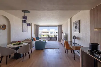 a living room with a couch and a table and chairs at Rixos Premium Magawish Bay View in Hurghada
