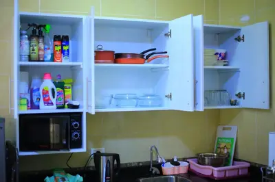 a kitchen with white cabinets with dishes and a sink at Sea Breeze in Hurghada
