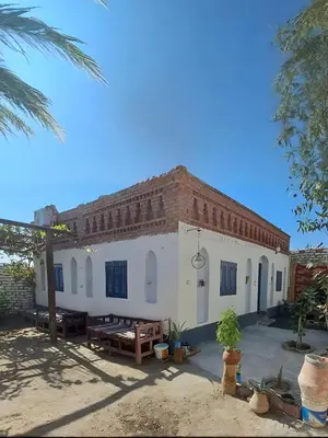 a large white building with a brick roof at Adam Guesthouse in Al Kawāmil Qiblī