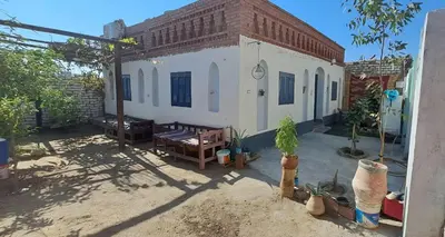 a small white building with a brick roof at Adam Guesthouse in Al Kawāmil Qiblī