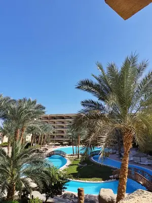 a view of the pool from the balcony of a hotel with palm trees at cozy sea view apartment palma resort in Hurghada