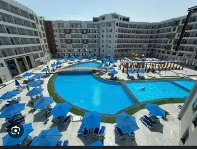 a large swimming pool with blue umbrellas and chairs at tiba golden resort in Hurghada