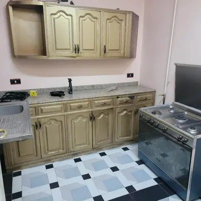 a kitchen with wooden cabinets and a stove at OS & MA Luxor APT in Luxor