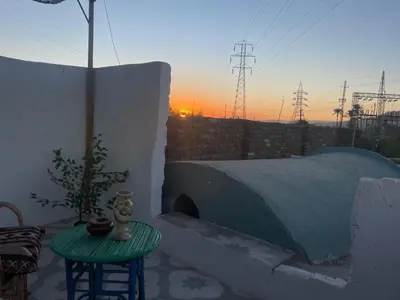 a room with a table and a bed with a sunset at Harmonia House in Al Karnak