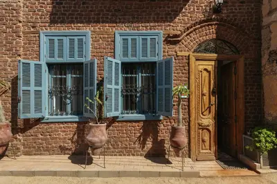 a brick building with blue windows and a door at Beit Felfel in Esna