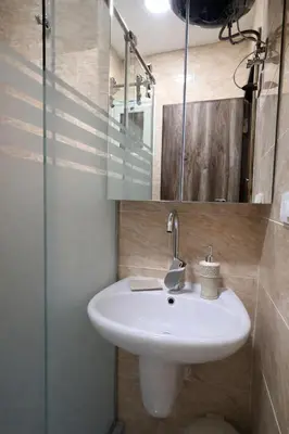 a bathroom with a white sink and a glass shower at Luxury Sea View Apt near Beach - 2 Pools - Balcony in Hurghada