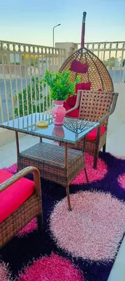 a glass table and two chairs on a rug at Gamal in Hurghada