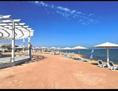 a beach with chairs and umbrellas and the ocean at Sea-Front Selena Bay Resort Apartment in Hurghada