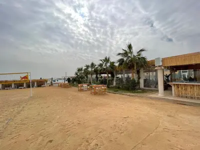 a beach with tables and palm trees and a building at Sea-Front Selena Bay Resort Apartment in Hurghada