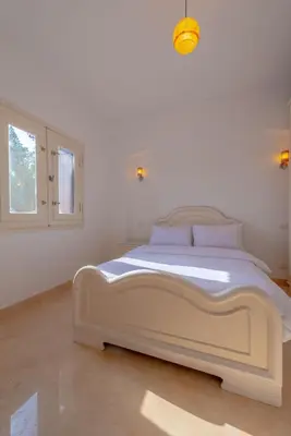 a large white bed in a white room with a window at VESTA - El Gouna Residence in Hurghada