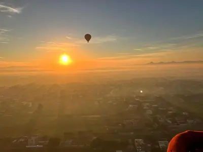a hot air balloon flying over a city at sunset at sunrise house in Luxor