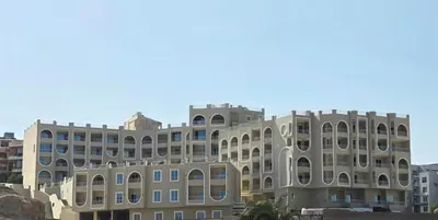 a building in front of a blue sky at Ramses Apartment in Hurghada