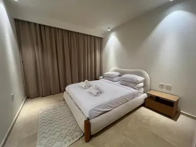 a bedroom with a bed with white sheets and towels at Ancient Sands 2BR | Ground Floor, Pool Access in Hurghada