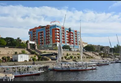 a large red and blue building with boats in the water at مول بلازا in Aswān