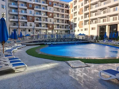 a large swimming pool with chairs and umbrellas in front of a building at Tiba golden resort in Hurghada