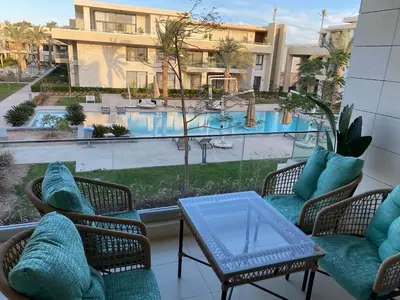a balcony with chairs and a table and a swimming pool at Contemporary Condo Studio in G-Cribs in El Gouna
