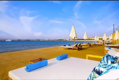 a beach with chairs and umbrellas and the water at Luxury Apartment In Azzurra Sahl Hashish 6G101 in Hurghada