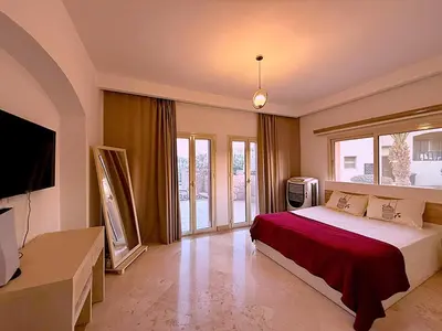 a bedroom with a bed and a tv andwindows at Luxury Apartment In Azzurra Sahl Hashish 6G101 in Hurghada