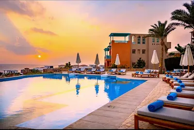 a pool at a resort with a sunset in the background at Luxury Apartment In Azzurra Sahl Hashish 6G101 in Hurghada