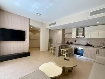 a living room with a table and a kitchen at Bright 1BR Apt - Free Beach And Pool In Mangroovy ElGouna in Hurghada