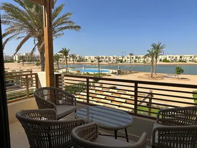 a balcony with chairs and a table and a pool at Colorful 1BR Apt-Free Pool & Lagoon Access In ElGouna in Hurghada