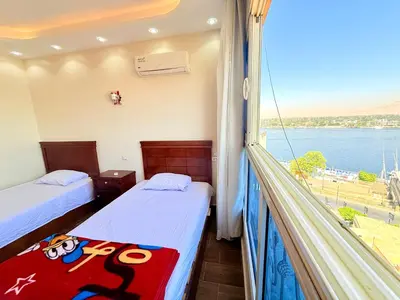 a room with two beds and a balcony with a view at Sun Palace House in Luxor
