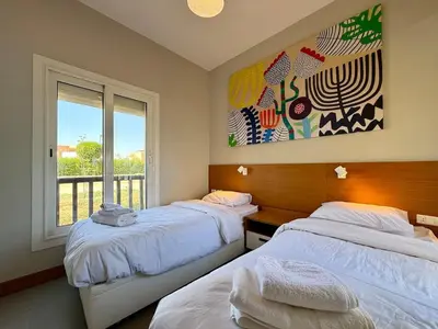 two beds in a room with a window and a painting at Scenic 2BR Ground Floor - Free Pool& Lagoon Access In ElGouna in Hurghada