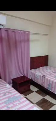 two beds in a room with pink curtains at قصر الحجر in Aswan