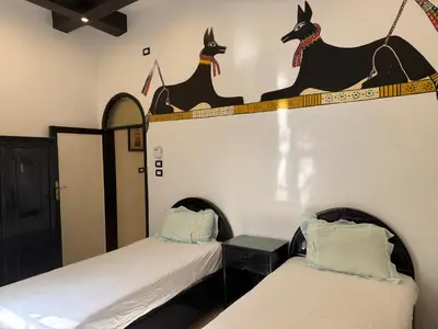 two beds in a room with two dogs on the wall at Ramla Palace House in Luxor
