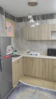 a kitchen with wooden cabinets and a stainless steel refrigerator at Nice flat in region Intercontinental in Hurghada