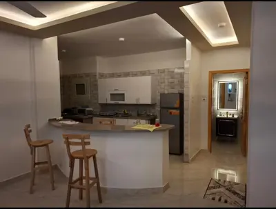 a kitchen with a counter and two bar stools at Villa Azad Elkber in Quseir