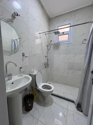 a white bathroom with a toilet and a sink at Orange guest house in Luxor