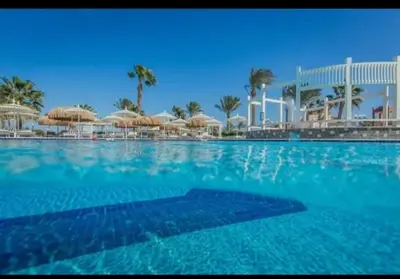 a large swimming pool with umbrellas and a resort at قرية ميراج باي للراحة والانسجام in Hurghada