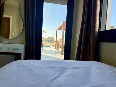 a bedroom with a bed and a mirror and a balcony at Sunny 4BR Villa Plus Nanny With Private Heated Pool And Jacuzzi In ElGouna in Hurghada