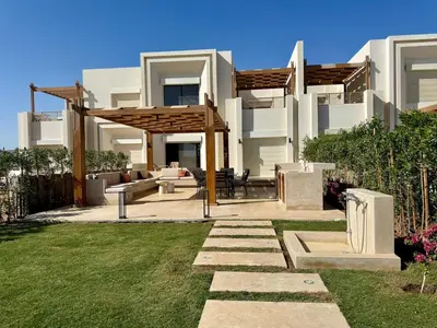 a backyard with a wooden pergola in front of a house at Premium 3BR Plus Nanny Villa -Free Pool And Lagoon Access In ElGouna in Hurghada