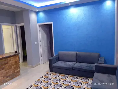 a living room with a couch and a blue wall at Red Ruby suites& flats HRG & Elgouna in El Gouna