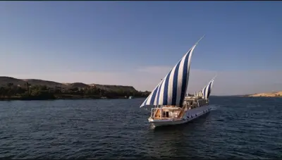 a boat with blue and white sails in the water at Soul of the nile Dahabyia in Al Baghdādī