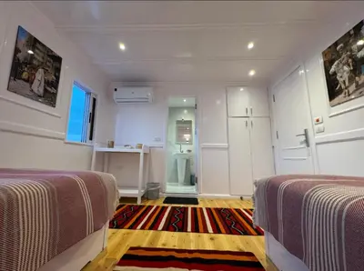 a white room with two beds and a hallway at Soul of the nile Dahabyia in Al Baghdādī