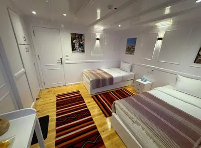 a small bedroom with two beds and a rug at Soul of the nile Dahabyia in Al Baghdādī