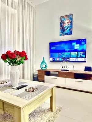 a living room with a tv and a vase with red roses at G Grips Grand 4 in El Gouna