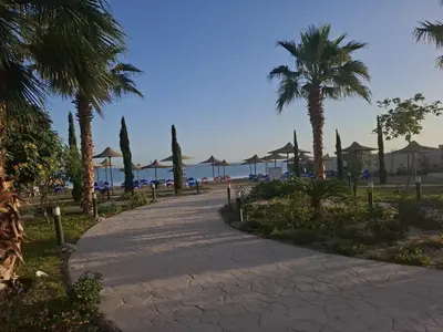 a walkway with palm trees and umbrellas on the beach at Casblanka beach in Hurghada