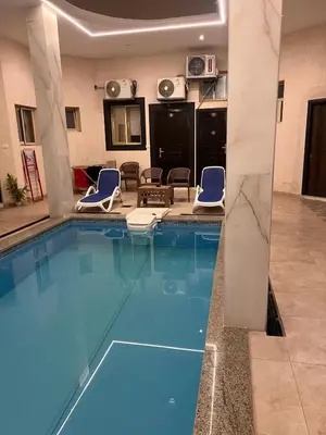a pool in a hotel room with two blue chairs at Sea Light Arabia in Hurghada