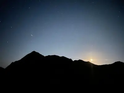 a silhouette of a mountain at night with the sun at malee cashie in Aswan