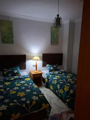 a bedroom with two beds and a table with a lamp at Apartment for Rent Hurghada, Oasis Marina Resort in Hurghada