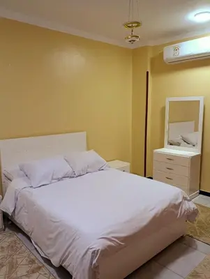 a bedroom with a white bed and a mirror at Lutos flower apartment 2 in Al Karnak