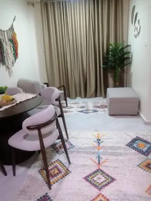 a living room with a table and chairs and a rug at بيت الاستجمام in Idfū