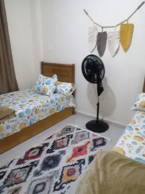 a bedroom with two beds and a fan in it at بيت الاستجمام in Idfū