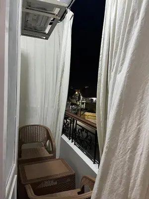 a balcony with a white curtain and a table and chairs at Dahabiya Apartment in Luxor