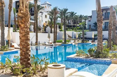 an image of a resort pool with palm trees at Stylishly furnished and quietly located apartment in Hurghada